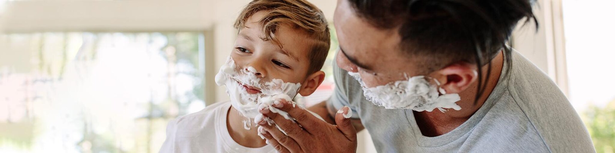 Vater und Sohn haben Rasieschaum im Gesicht