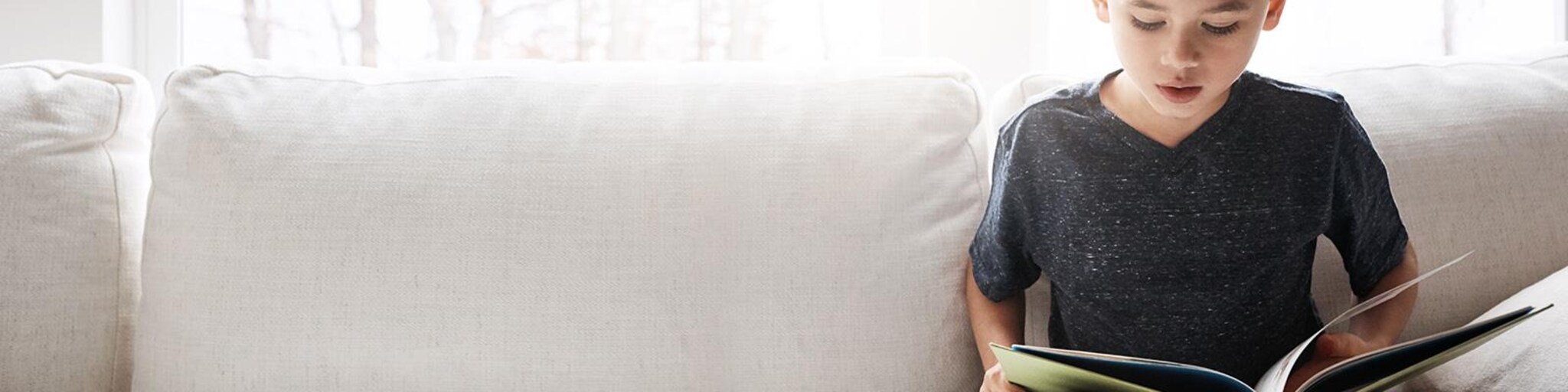 junge sitzt mit buch auf der couch