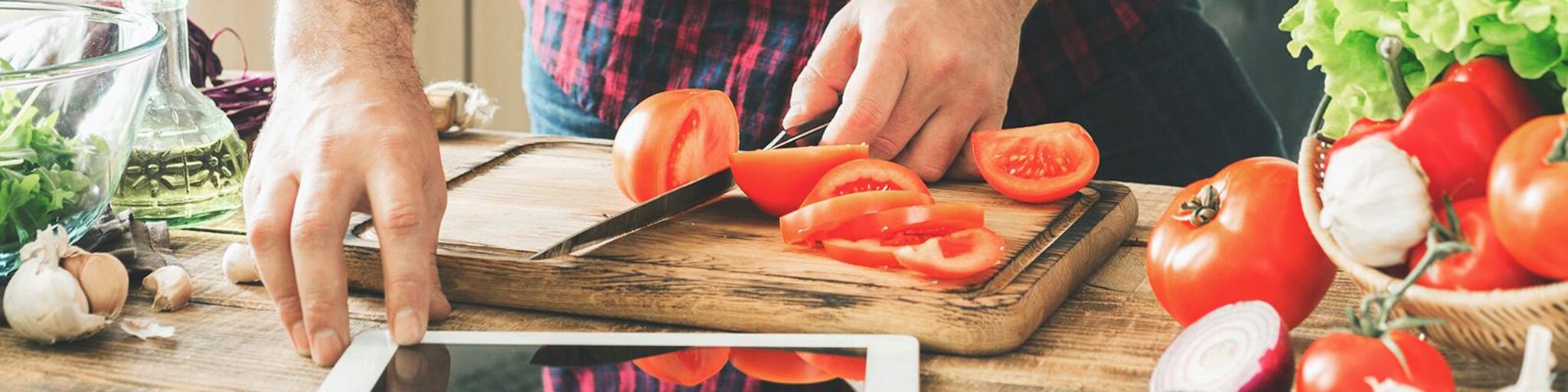 Junger Mann beim schneiden von Tomaten