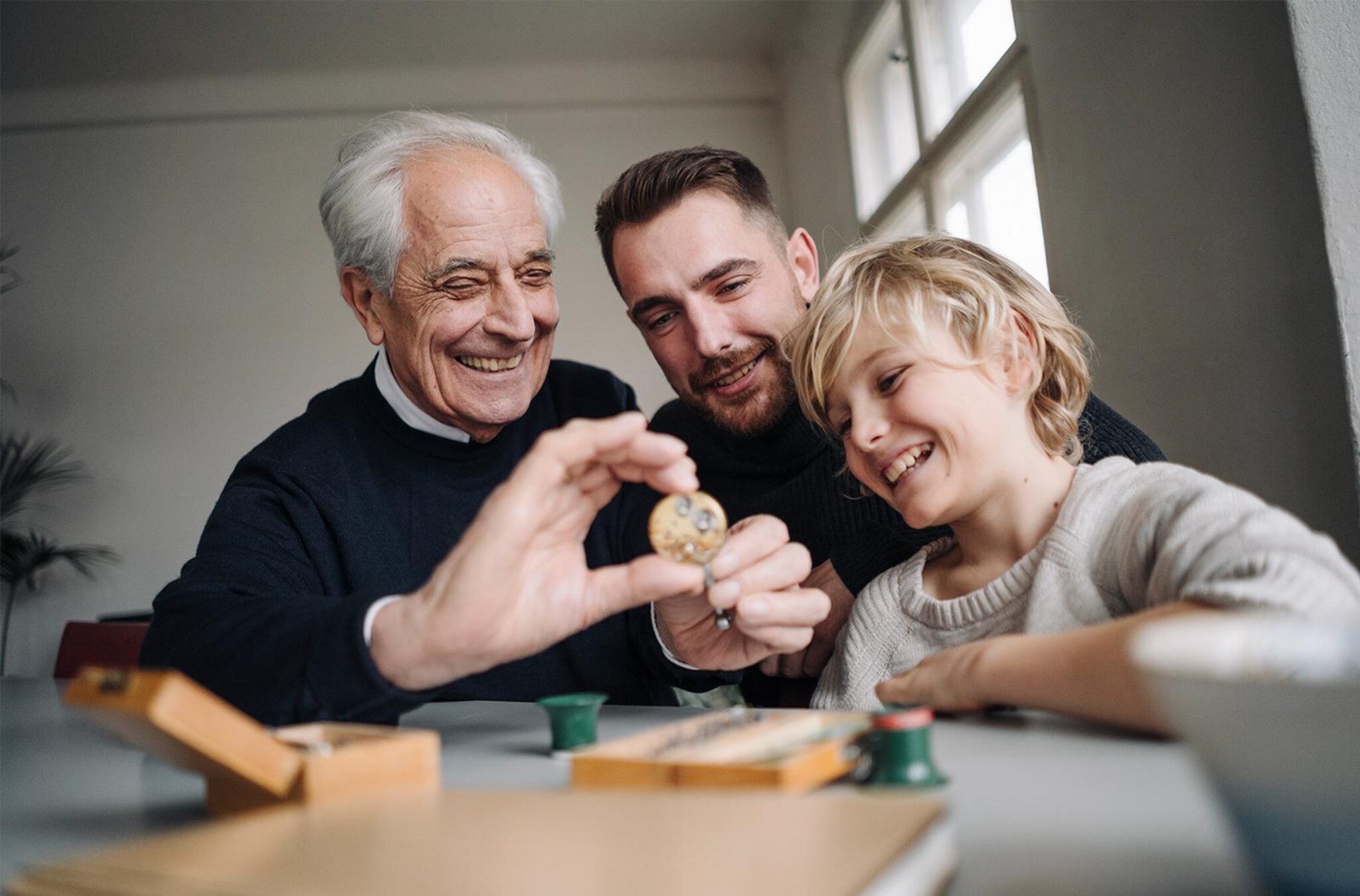Vater, Sohn und Enkel reparieren zusammen ein Uhrwerk