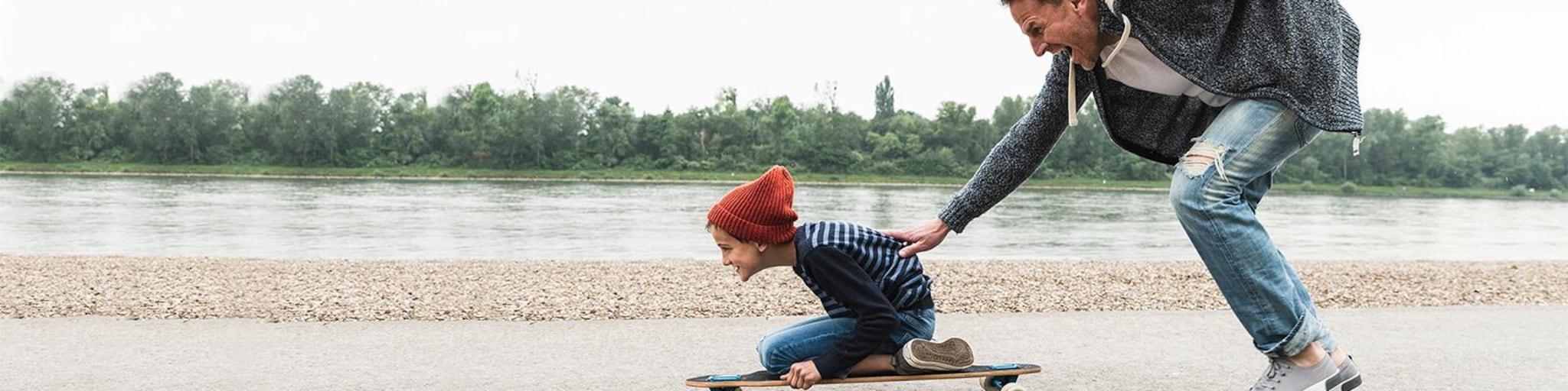 Vater schiebt Sohn auf einem Skateboard